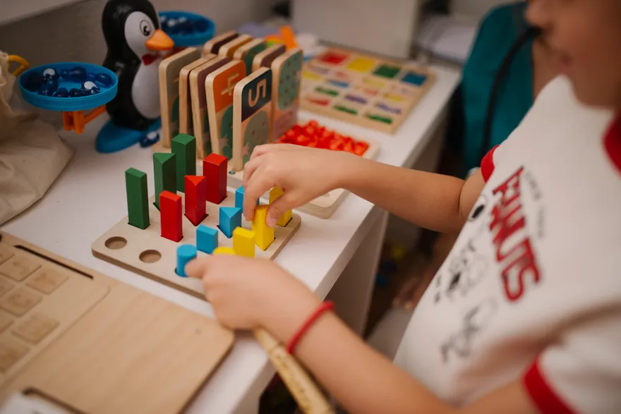 A child engaged in a colorful block-building activity at a table of learning toys