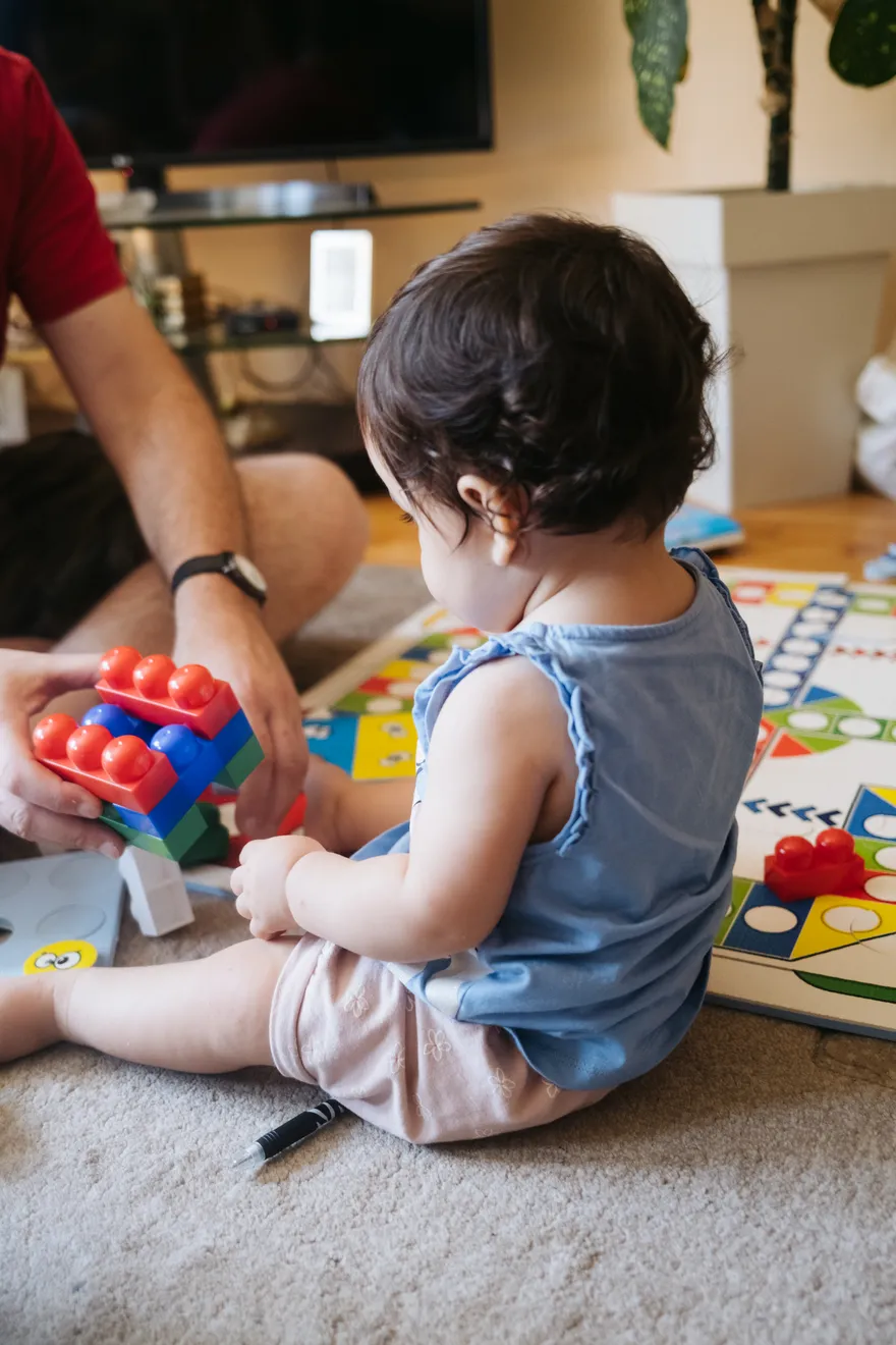 A child and an adult playing with building blocks together on the floor